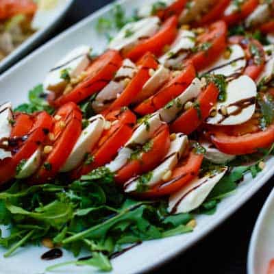 Caprese salad typically contains tomatoes sliced mozzarella fresh basil olive oil salt pepper and a balsamic drizzle